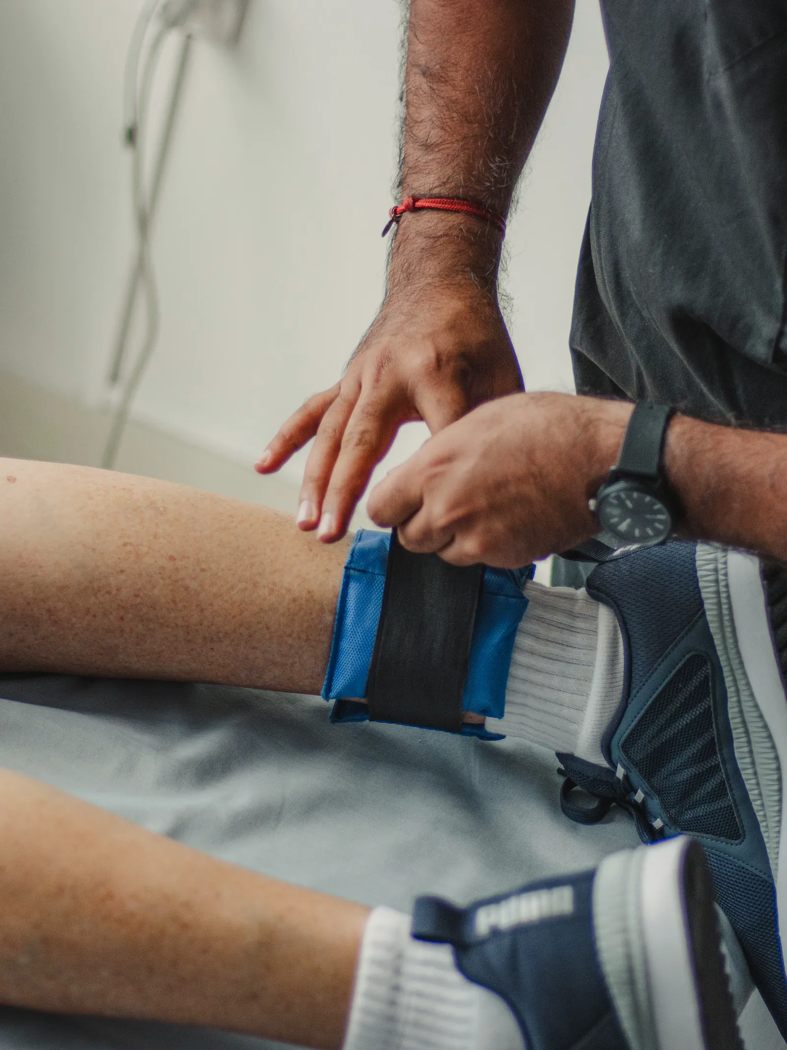 Practitioner securing the cold wave therapy unit around a client's knee