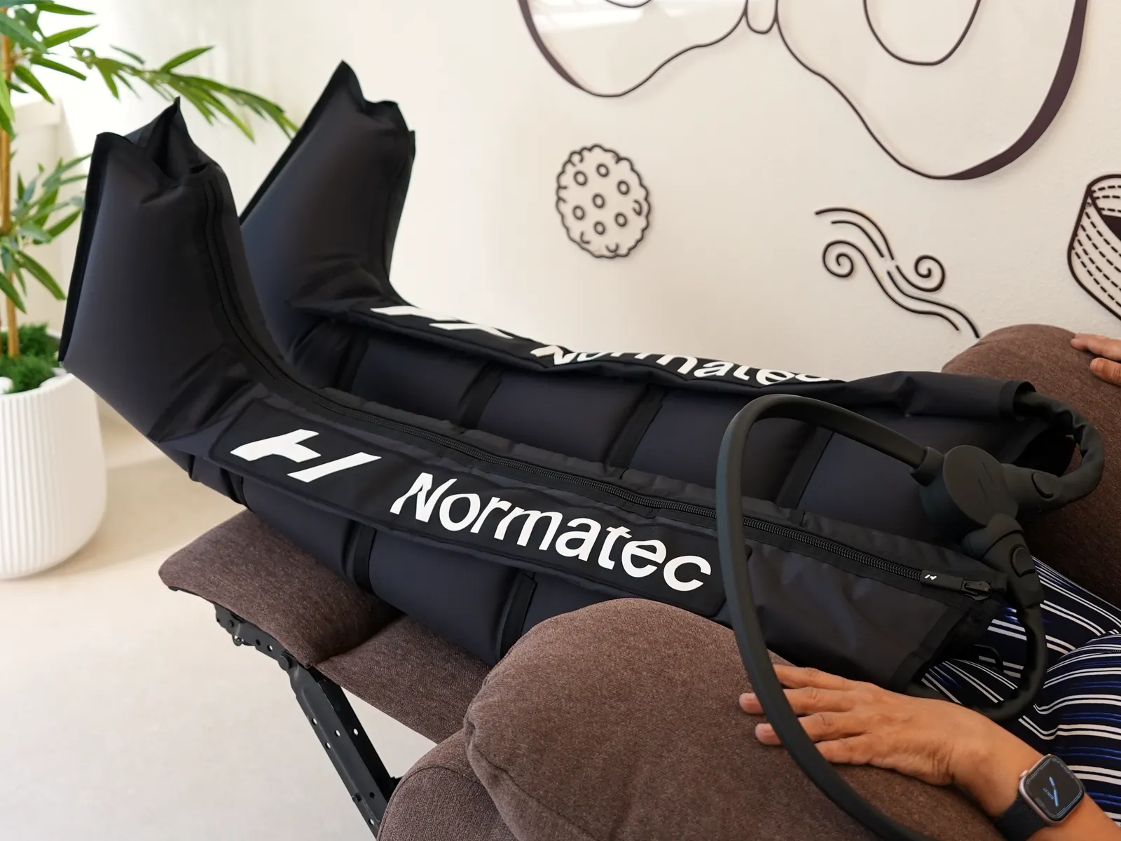 Client resting in Normatec compression boots in the recovery suite