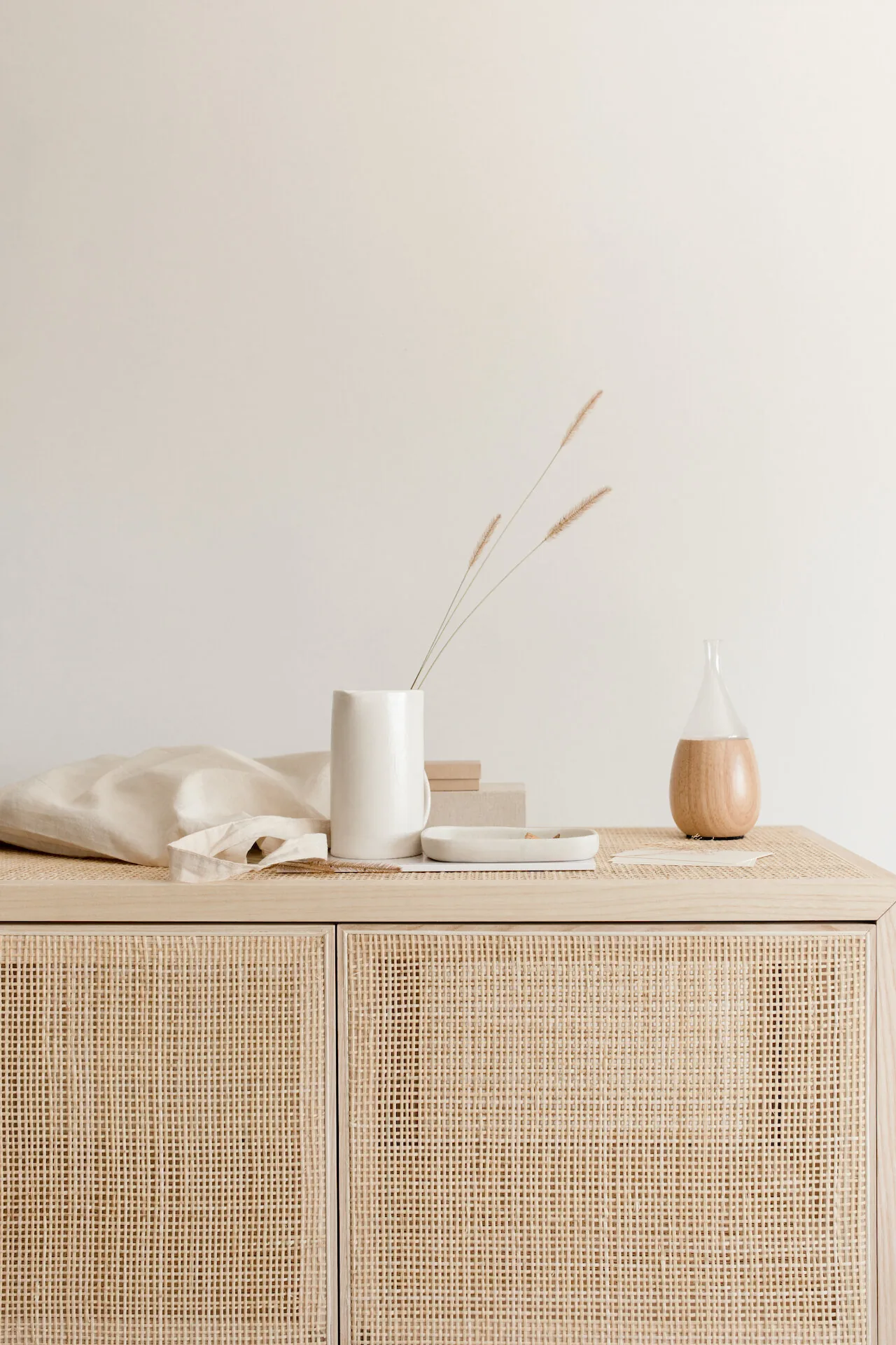 Calm studio corner with rattan cabinet and ceramics
